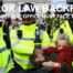 Police officers carry a woman away as protesters hold signs supporting Palestine Action during a London demonstration.
